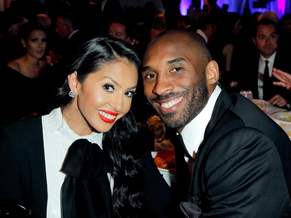 Vanessa Bryant (left) and Kobe Bryant (right) touching heads to pose for a photo in black and white attire