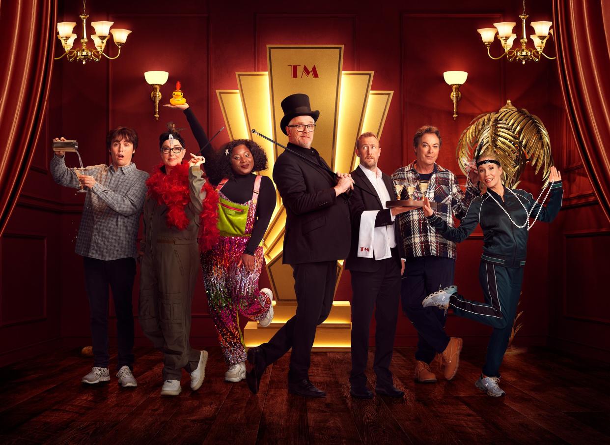  Taskmaster season 16 line up posing with host Greg Davies and assistant Alex Horne. 