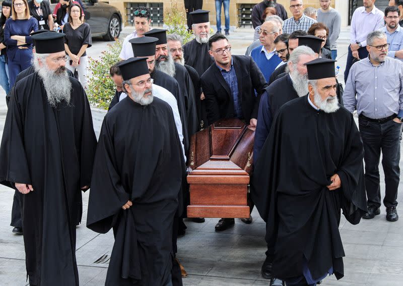 Greek Orthodox priests carry the coffin of the late Archbishop Chrysostomos II outside the Holy Archbishopric in Nicosia