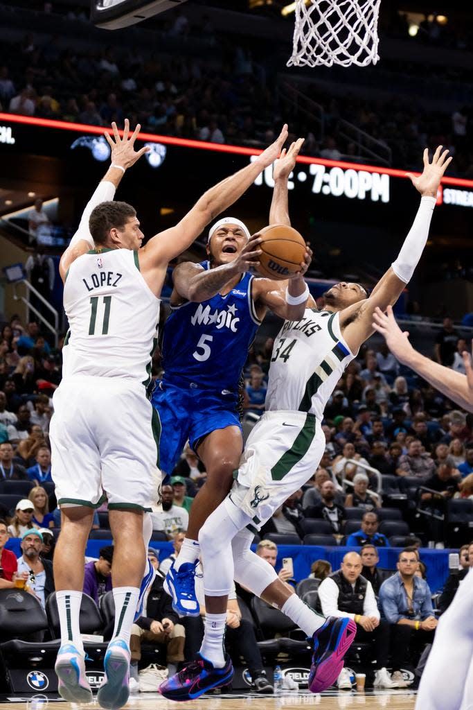 Orlando Magic forward Paolo Banchero attempts a layup over Bucks center Brook Lopez and forward Giannis Antetokounmpo during the first half Saturday at Amway Center. Banchero scored 26 points.