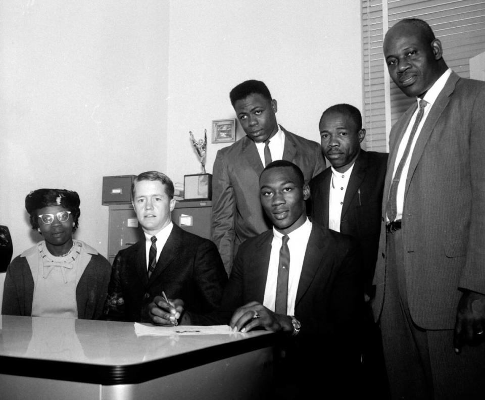 Raymond Bellamy, from Lincoln High School, signs a contract. Seated, from left is Mary Bellamy, an unidentified gentleman, and Raymond Bellamy. Standing are Sylvester Bellamy, Lincoln’s Coach Shannon and Principal Joseph Bivens.