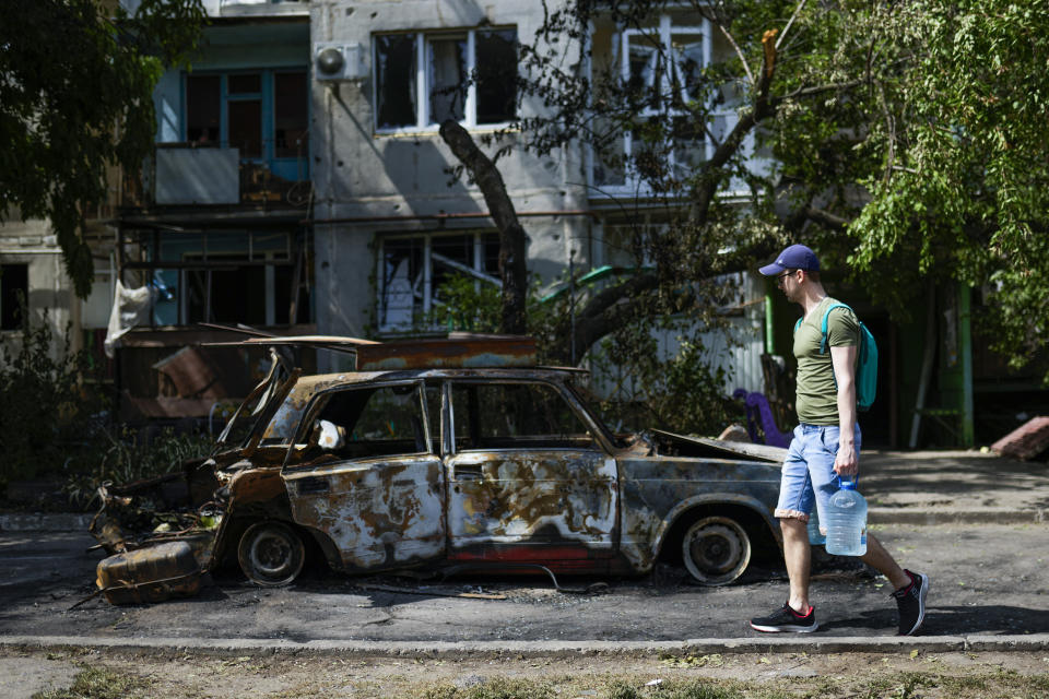 FILE - A man carries water in front of an apartment building damaged in an overnight missile strike, in Sloviansk, Ukraine, May 31, 2022. The U.S. intelligence community has launched a review of how it judges foreign governments’ will and ability to fight. American spy agencies underestimated Ukraine's will to fight while overestimating Russia's ability to overrun the country, even as it accurately predicted Russian President Vladimir Putin would order an invasion. (AP Photo/Francisco Seco, File)