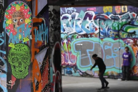 Anti-Brexit graffiti is seen in an underground area as people skateboard in London