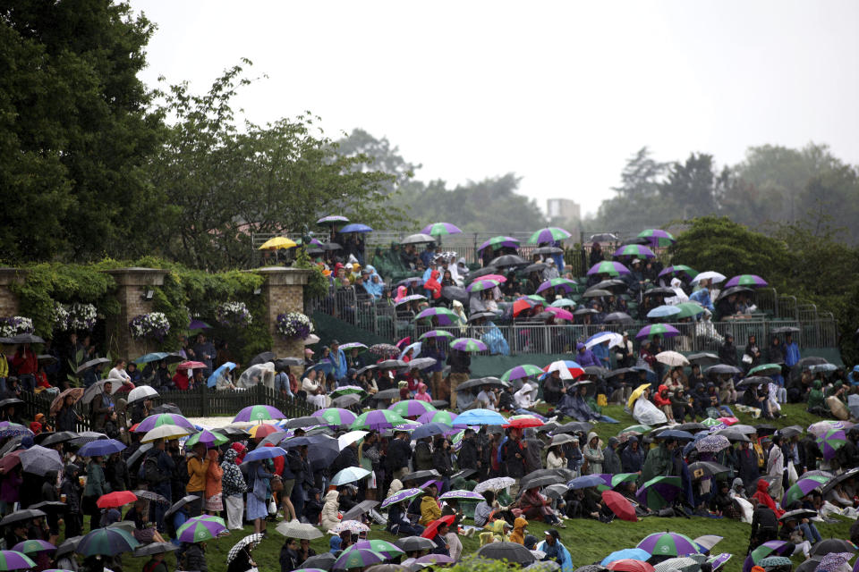 Los espectadores se cubren de la lluvia durante el segundo día del torneo de Wimbledon, el martes 4 de julio de 2023, en Londres. (Steven Paston/PA vía AP)