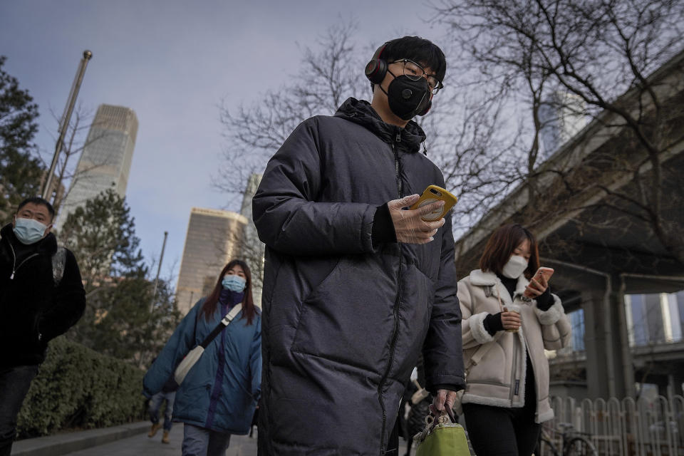 A man wearing a face mask and a disposable gloves to help curb the spread of the coronavirus heads to work with other masked people during the morning rush hour in Beijing, Monday, Jan. 11, 2012. Chinese health authorities say scores more people have tested positive for coronavirus in Hebei province bordering on the capital Beijing. The outbreak focused on the Hebei cities of Shijiazhuang and Xingtai is one of China's most serious in recent months and comes amid measures to curb the further spread during next month's Lunar New Year holiday. (AP Photo/Andy Wong)