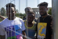 Migrants from Cameroon stand by the fence at the refugee camp in the village of Vydeniai, Lithuania, Saturday, July 10, 2021. European Union member Lithuania has declared a state of emergency due to an influx of migrants from neighboring Belarus in the last few days. Lithuania's interior minister said late Friday that the decision, proposed by the State Border Guard Service, was necessary not because of increased threats to the country of 2.8 million but to put a more robust system in place to handle migrants. (AP Photo/Mindaugas Kulbis)