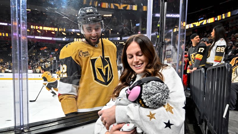 Vegas Golden Knights right wing Michael Amadio, left, looks at his newborn daughter, Scottie, who is held by his wife, Bronwyn Amadio, during warmups before an NHL hockey game against the Los Angeles Kings, Thursday, Dec. 28, 2023, in Las Vegas.