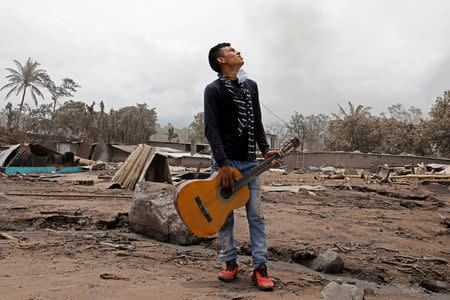 Brian Rivera, who lost 13 members of his family during the eruption of the Fuego volcano, holds his sister's guitar near debris of his home at San Miguel Los Lotes, Escuintla, Guatemala 7 June, 2018. REUTERS/Carlos Jasso