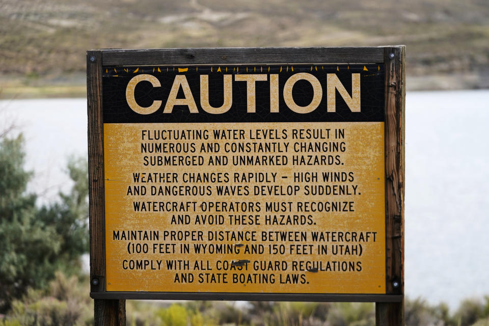 A sign cautioning fluctuating water levels is displayed at Firehole Canyon on the far northeastern shore of Flaming Gorge Reservoir on Friday, Aug. 5, 2022, in Wyoming. A boating and fishing paradise on the Utah-Wyoming line, Flaming Gorge is beginning to feel the effects of the two-decade megadrought gripping the southwestern U.S. (AP Photo/Rick Bowmer)