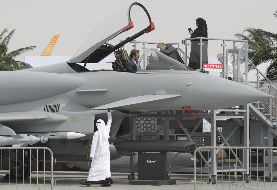 An Emirati woman, top right, and others view a replica of the Eurofighter Typhoon jet during the opening day of the Dubai Airshow in Dubai, United Arab Emirates, Sunday Nov. 17, 2013. The Dubai Airshow is seen as an increasingly important barometer on the state of the industry and the rising roles of the big-spending Gulf carriers Etihad, Qatar Airways and Emirates as they compete for routes and critical stopover traffic between Asia and Europe and the Americas. (AP Photo/Kamran Jebreili)