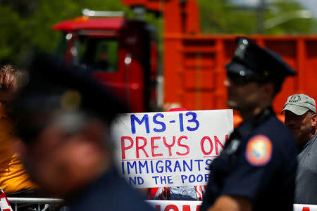 U.S. president Trump supporters hold placards against MS-13 as New York Police stand guard at the street during a forum about Central American-based Mara Salvatrucha (MS-13) gang organization at the Morrelly Homeland Security Center in Bethpage, New York, U.S., May 23, 2018. REUTERS/Eduardo Munoz