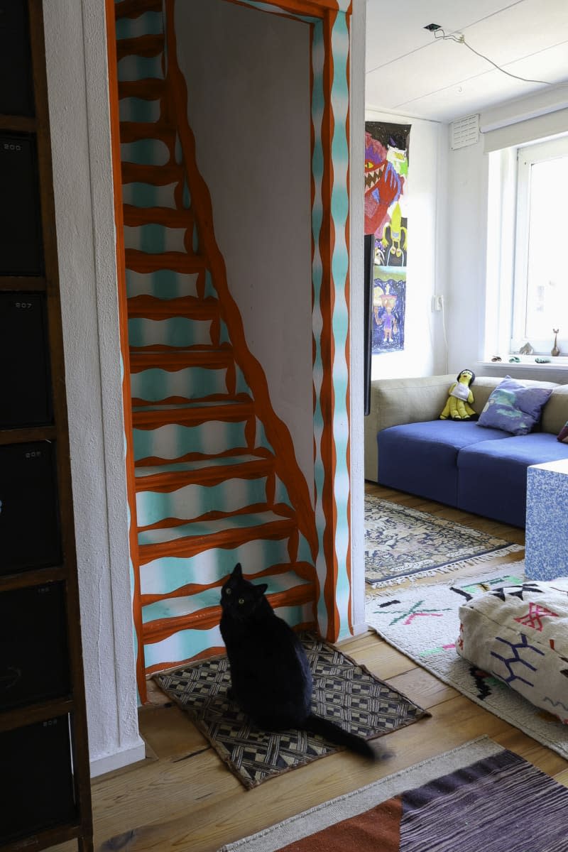 black cat sitting at the bottom of colorful stairs