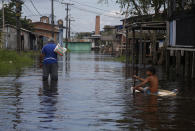 A boy uses a fridge door to float across a street flooded by the rise of the Negro river in Iranduba, Amazonas state, Brazil, Monday, May 23, 2022. The Amazon region is being hit hard by flooding with 35 municipalities that are facing one of their worst floods in years and the water level is expected to rise over the coming months. (AP Photo/Edmar Barros)