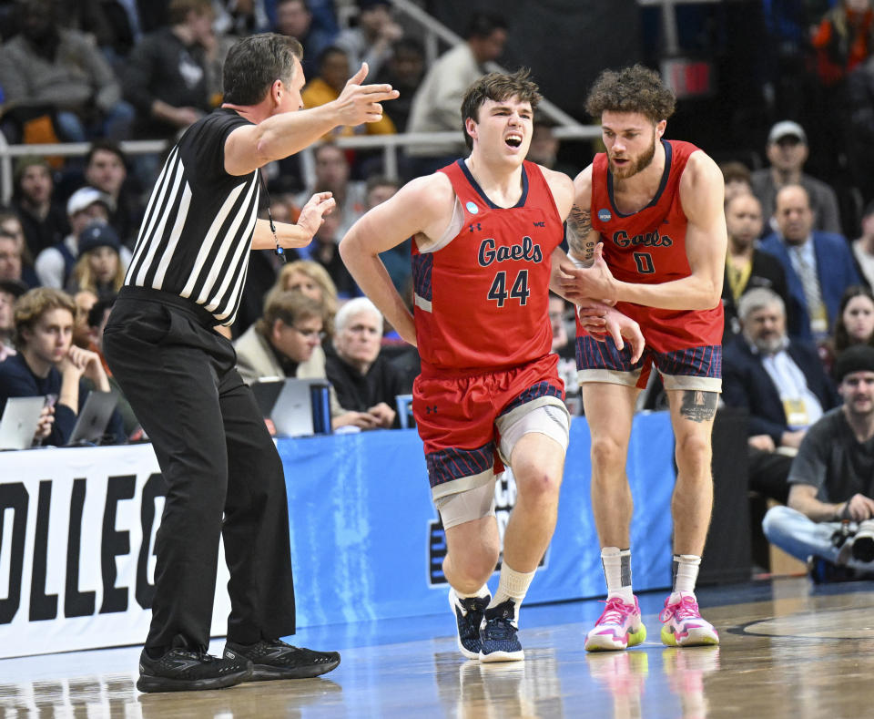 A official signals the bench that Saint Mary's guard Alex Ducas (44) is injured as teammate Logan Johnson (0) checks on on him during the first half of a second-round college basketball game against UConn in the men's NCAA Tournament on Sunday, March 19, 2023, in Albany, N.Y. (AP Photo/Hans Pennink)