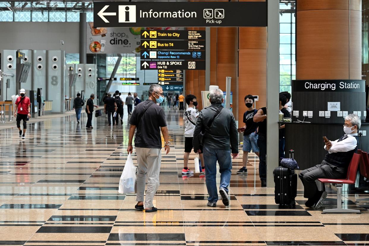 A traveller (R) waits in the departure hall of Changi International Airport in Singapore on March 15, 2021. (Photo by ROSLAN RAHMAN/AFP via Getty Images)