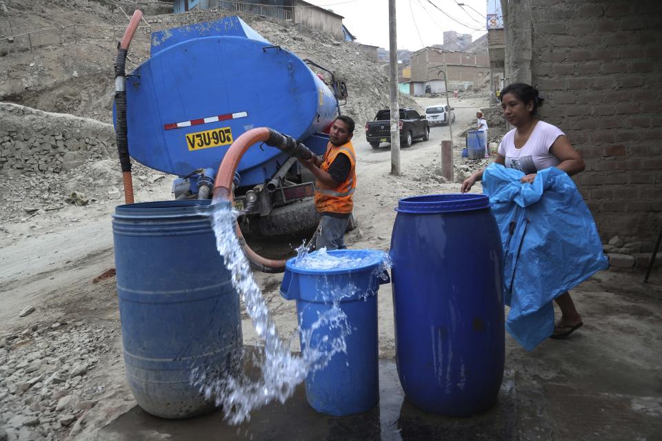 FILE - In this March 13, 2020 file photo, a worker fills a container with water from a water truck at the Villa Maria del Triunfo shantytown in Lima, Peru. The poor who live in the hills of Peru's capital, for whom a basic supply of clean water is a daily struggle, are finding it hard to meet the basic hygiene recommendations by health officials to avoid contracting the new coronavirus: Wash your hands for at least 20 seconds. (AP Photo/Martin Mejia, File)