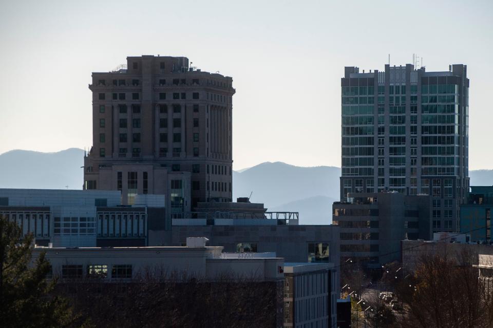 The Blue Ridge Mountains rise behind the Buncombe County Courthouse, left, and the Arras Hotel, Nov. 28, 2023, in Asheville.