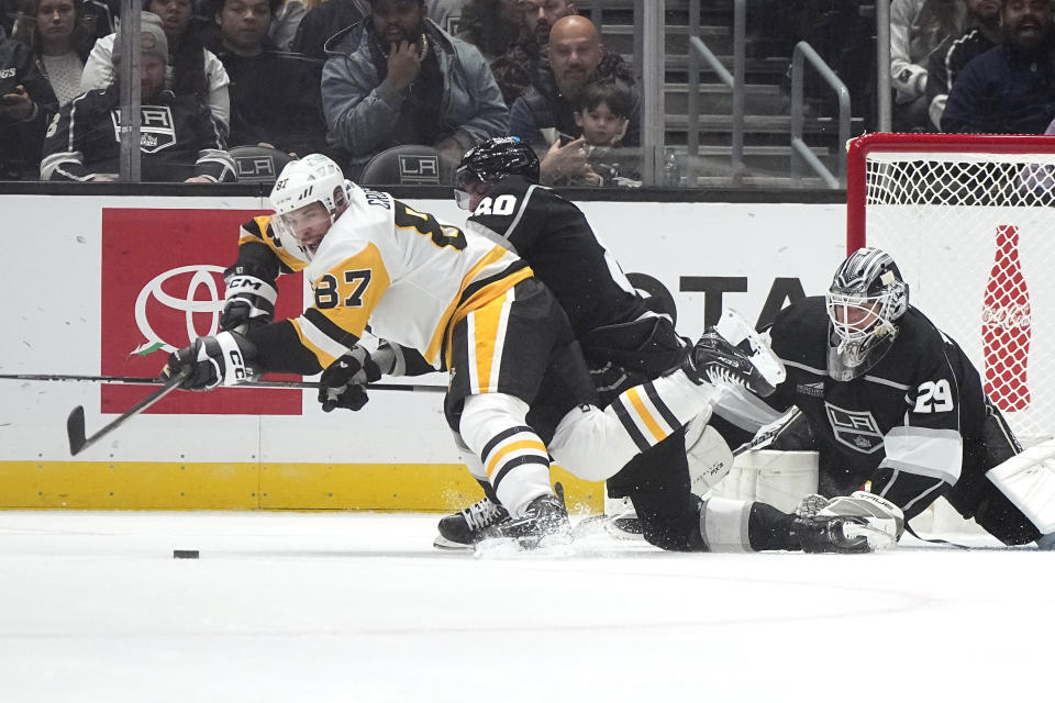 Pittsburgh Penguins center Sidney Crosby, left, tries to pass the puck while under pressure from Los Angeles Kings left wing Pierre-Luc Dubois, center, while goaltender Pheonix Copley watches during the second period of an NHL hockey game Thursday, Nov. 9, 2023, in Los Angeles. (AP Photo/Mark J. Terrill)