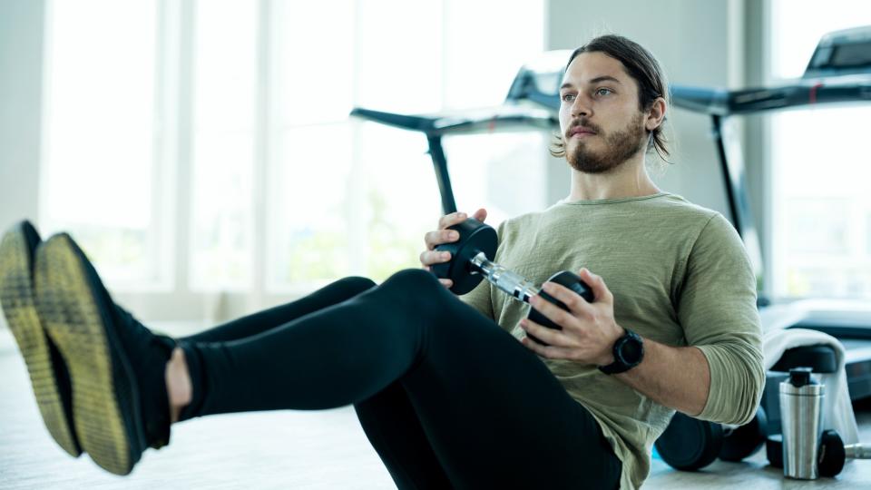 Man doing Russian twists with a dumbbell.