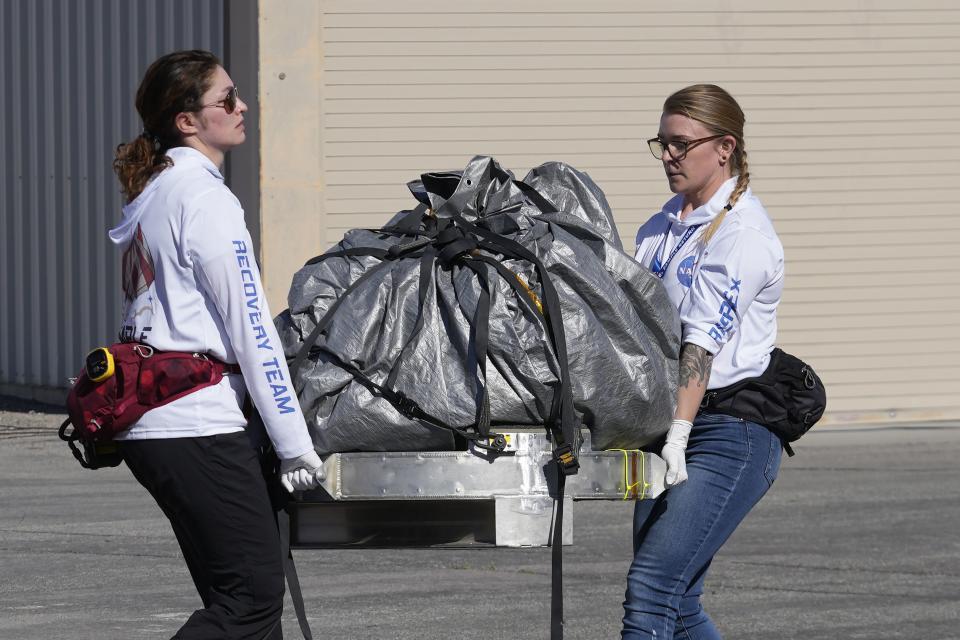 Recovery team members carry a capsule containing NASA’s first asteroid samples to a temporary clean room at Dugway Proving Ground in Utah on Sunday, Sept. 24, 2023. The Osiris-Rex spacecraft released the capsule following a seven-year journey to asteroid Bennu and back. | Rick Bowmer, Associated Press