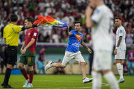 A pitch invader runs across the field with a rainbow flag during the World Cup group H soccer match between Portugal and Uruguay, at the Lusail Stadium in Lusail, Qatar, Monday, Nov. 28, 2022. (AP Photo/Abbie Parr)