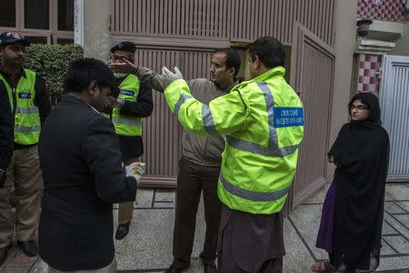 A member of the crime scene investigation unit speaks to the owners of a home that has been robbed in Lahore January 13, 2015. REUTERS/Zohra Bensemra