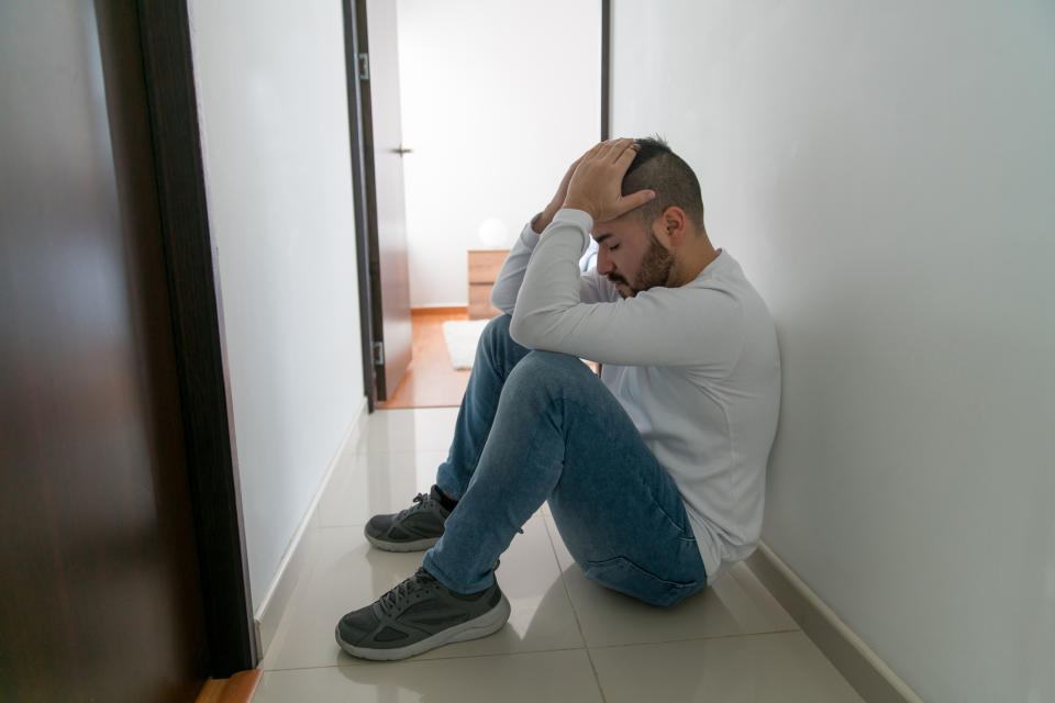 A distraught-looking man slumped in a hallway