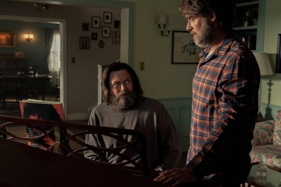 Frank (Murray Bartlett) stands over Bill (Nick Offerman) as he plays piano in episode 3 of The Last of Us.