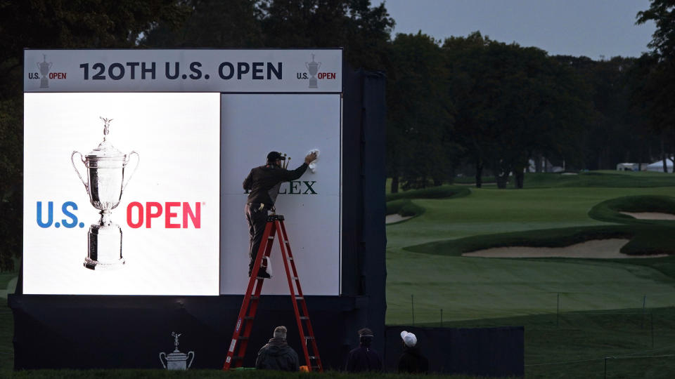 A worker prepares the scoreboard along the 18th green at sunrise prior to a practice round before the U.S. Open Championship golf tournament, Wednesday, Sept. 16, 2020, at the Winged Foot Golf Club in Mamaroneck, N.Y. (AP Photo/Charles Krupa)