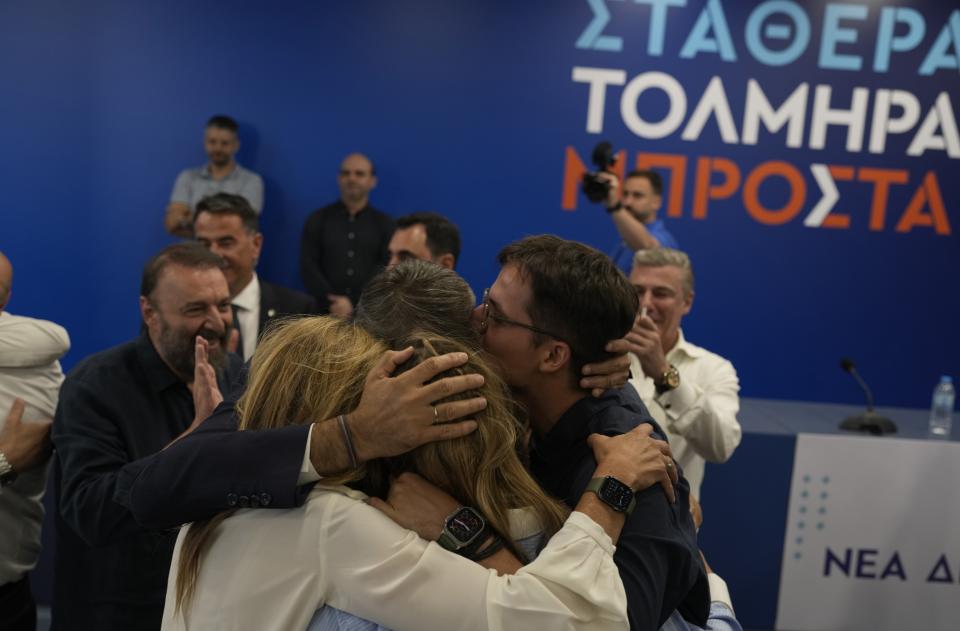 Kyriakos Mitsotakis leader of center-right New Democracy hugs his family at the headquarters of the party in Athens, Greece, Sunday, June 25, 2023. Greece's conservative New Democracy party has won a landslide victory in the country's second election in five weeks, with partial official results showing it gaining a comfortable parliamentary majority to form a government for a second four-year term. (AP Photo/Petros Giannakouris)