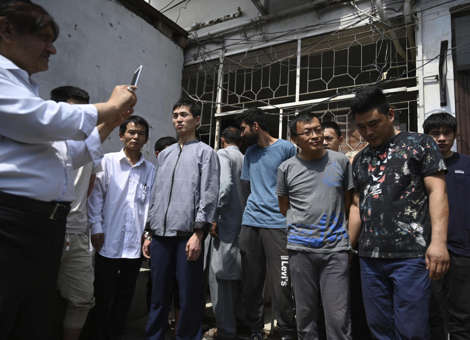 FILE - In this May 9, 2019, file photo, a Pakistani official takes pictures of detained Chinese nationals on alleged involvement in a trafficking gang to lure Pakistani women into fake marriages, arrive at a court in Islamabad, Pakistan. Christian girls are being lured into marriages with Chinese men, whom they are told are Christian and wealthy only to end up trapped in China, married to men who are neither Christian nor well-to-do, and some are unable to return home. (AP Photo/B.K. Bangash)