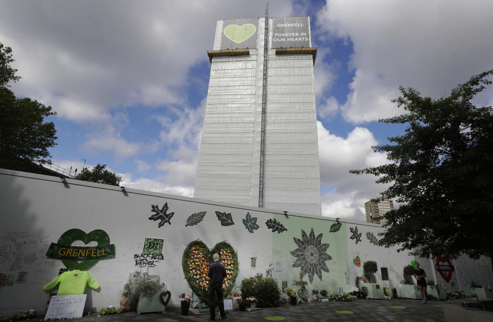 A man looks at tributes placed near Grenfell Tower in London, Sunday, June 14, 2020. Britain is marking the third anniversary of the Grenfell Tower fire with a virtual church service to remember the 72 people who died in the blaze. Sunday marks three years since a small kitchen fire in the west London public-housing block turned into the worst domestic blaze in the country since World War II. (AP Photo/Kirsty Wigglesworth)