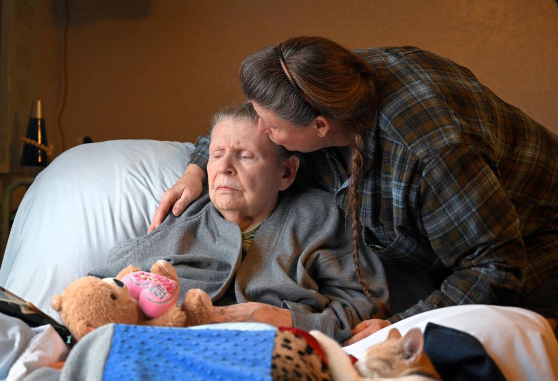 Tami DeFoe gives her mother Ellen DeFoe, 83, a kiss on the forehead during a visit to the home of Ellen’s caregiver, Carol Dowell.