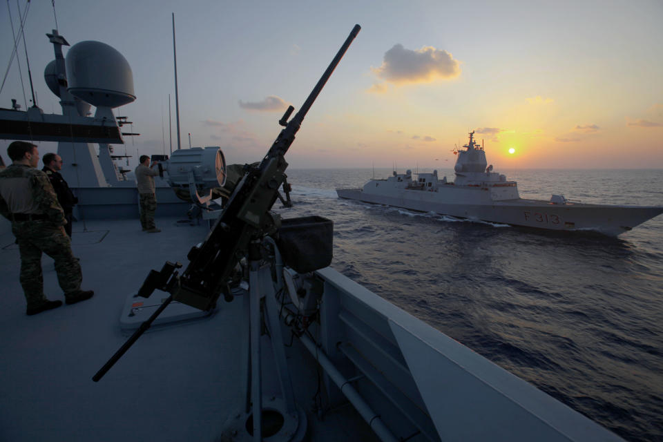 A crew member of the Danish warship Esbern Snare looks at the Norwegian warship "Helge Ingstad" as they pass each other during a sunset at sea between Cyprus and Syria, Sunday, Jan. 5, 2014. Two cargo ships and their warship escorts set sail at waters near Syria where they will wait for orders on when they can head to the Syrian port of Latakia to pick up more than 1,000 tons of chemical agents. (AP Photo/Petros Karadjias)