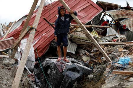 Ikhmal Yudanto, 15, stands on his mother's car at his destroyed house hit by an earthquake, in Balaroa neighbourhood, Palu, Central Sulawesi, Indonesia, October 11, 2018. Yudanto is helping his older brother to recover the car, which has been stuck in the ground since the earthquake. REUTERS/Jorge Silva