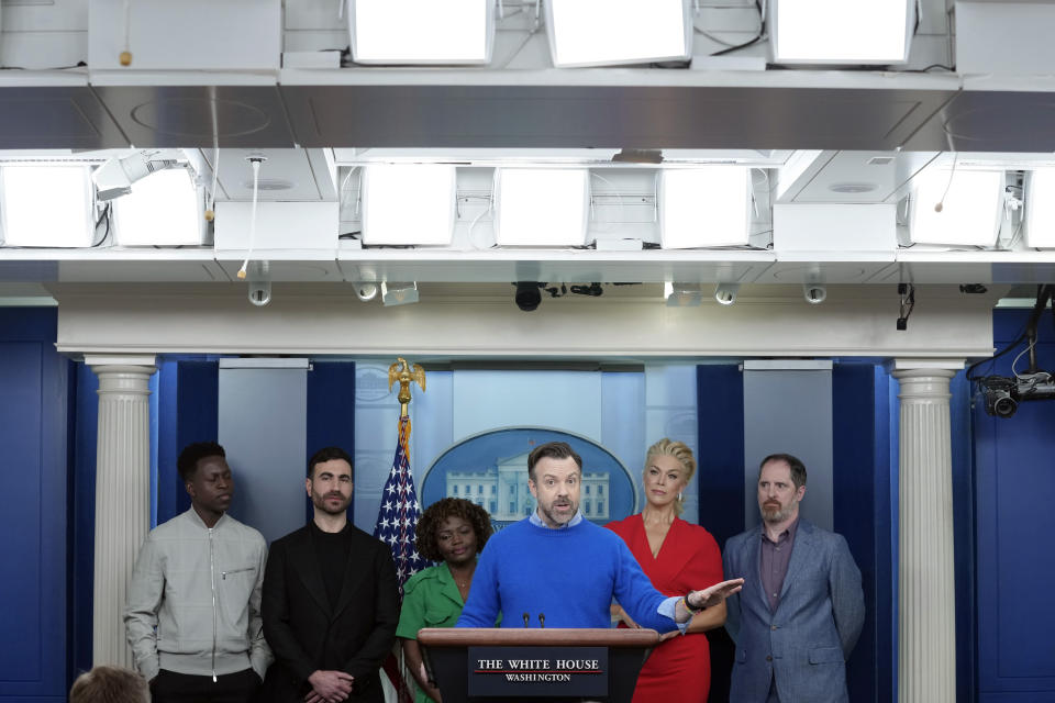 Jason Sudeikis, fourth from left, who plays the title character in the Apple TV+ series “Ted Lasso”, joins White House press secretary Karine Jean-Pierre, third from left, and fellow cast members, from left, Toheeb Jimoh, Brett Goldstein, Hannah Waddingham, and Brendan Hunt, during the daily press briefing at the White House in Washington, Monday, March 20, 2023. (AP Photo/Susan Walsh)