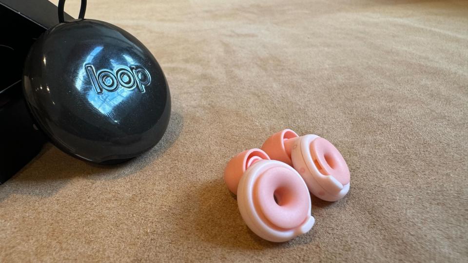 Loop Switch earbuds on a pink surface next to the case