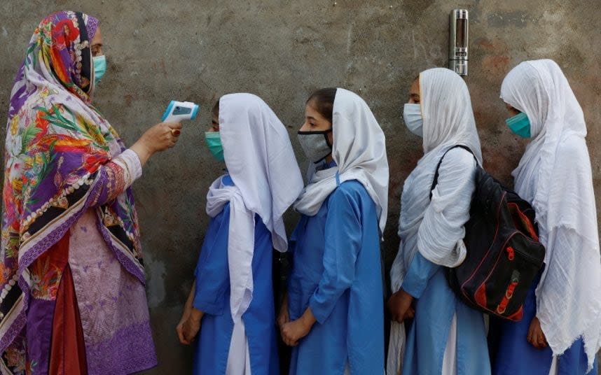 Students wear protective masks as they have their temperature checked before entering a class, after government allowed reopening of schools from grade six to eight amid the coronavirus disease (COVID-19) pandemic, in Peshawar, Pakistan - Fayaz Aziz/REUTERS