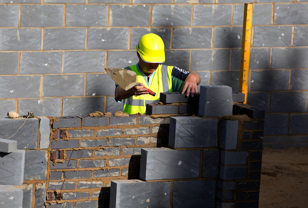 A worker lays bricks for a residential home at a building site in north London as UK construction growth falls