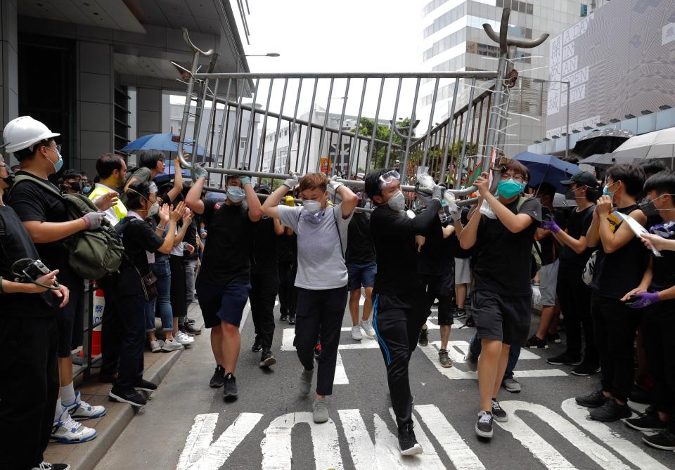 Protesters carry barricades to surround the police headquarters in Hong Kong on Friday, June 21, 2019. Several hundred mainly student protesters gathered outside Hong Kong government offices Friday morning, with some blocking traffic on a major thoroughfare, after a deadline passed for meeting their demands related to controversial extradition legislation that many see as eroding the territory's judicial independence. (AP Photo/Vincent Yu)