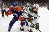 Minnesota Wild's Joel Eriksson Ek (14) and Edmonton Oilers' Cody Ceci (5) vie for the puck during the third period of an NHL hockey game Friday, Dec. 9, 2022, in Edmonton, Alberta. (Jason Franson/The Canadian Press via AP)