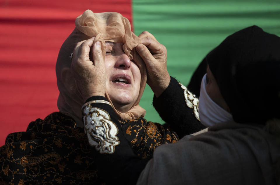 A woman wipes the tears of one the family members of Basharat Ahmad Zargar during his funeral in Srinagar, Indian-controlled Kashmir, Sunday, Feb.14, 2021. Zargar, who was working at a power project, was among the dozens killed after a part of a Himalayan glacier broke off on February 7 sending a devastating flood downriver slamming into two hydropower projects in northern India. (AP Photo/Mukhtar Khan)