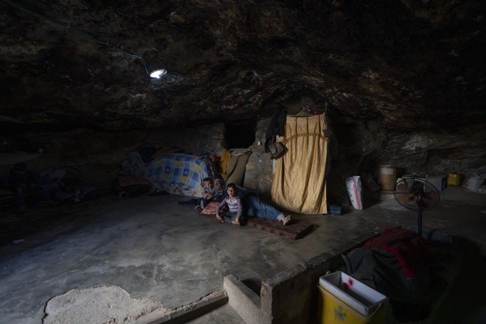 Palestinian Issa Abu Eram rests with two of his twelve children at a cave that is part of his house, in the West Bank Beduin community of Jinba, Masafer Yatta, Friday, May 6, 2022. Israel's Supreme Court has upheld a long-standing expulsion order against eight Palestinian hamlets in the occupied West Bank, potentially leaving at least 1,000 people homeless. (AP Photo/Nasser Nasser)