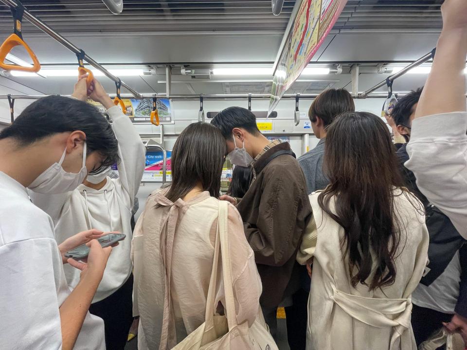 A group of people standing on a subway in Tokyo, Japan.