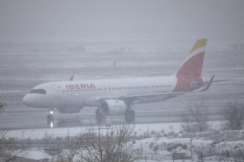 A passenger plane is seen on the ground of the Madrid airport during a heavy snowfall in downtown, Spain, Saturday, Jan. 9, 2021. A persistent blizzard has blanketed large parts of Spain with 50-year record levels of snow, halting traffic and leaving thousands trapped in cars or in train stations and airports that suspended all services as the snow kept falling on Saturday. (Jesus Hellin/Europa Press via AP)