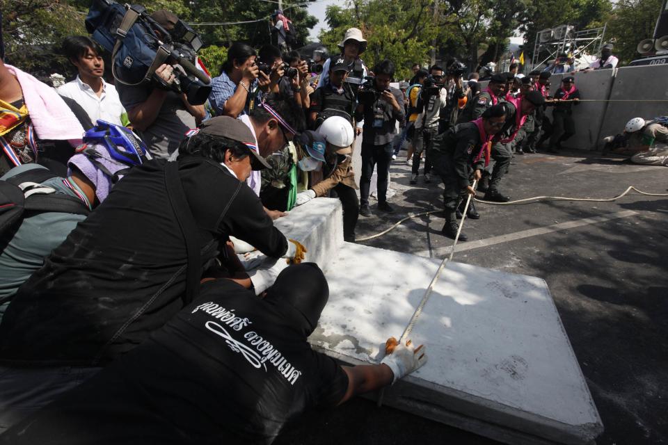 Riot police officers help anti-government protesters pull down a barricade near the metropolitan police headquarters in Bangkok December 3, 2013. Thailand's government ordered police to stand down and allow protesters into state buildings on Tuesday, removing a flashpoint for clashes and effectively bringing an end to days of violence in Bangkok in which five people have died. REUTERS/Kerek Wongsa (THAILAND - Tags: POLITICS CIVIL UNREST)
