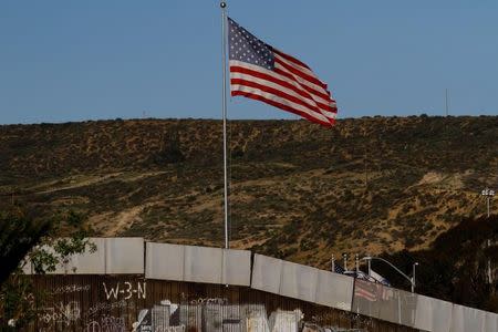 A U.S. flag is seen next to a section of the wall separating Mexico and the United States, in Tijuana, Mexico, January 28, 2017. REUTERS/Jorge Duenes