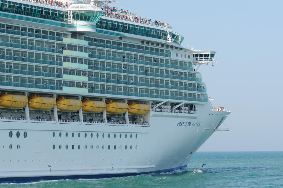 Port Canaveral, FL, USA - May 8, 2011: The Royal Caribbean Cruise ship &amp;amp;amp;amp;amp;amp;amp;amp;amp;quot;Freedom of the of the Seas&amp;amp;amp;amp;amp;amp;amp;amp;amp;quot; headed to sea from Port Canaveral, Florida.. A Bottle-nosed Dolphin leaps from the bow wake.