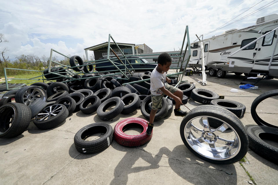 Cameron Arvie, 11, climbs on tires strewn by Hurricane Laura, at the family's destroyed auto detailing business in Lake Charles, La., in the aftermath of Hurricane Laura, Sunday, Aug. 30, 2020. (AP Photo/Gerald Herbert)