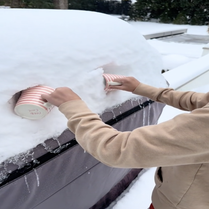 snow from a grill cover being scooped into two mugs